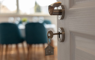 Open door into dining room with key in lock and small metal home keychain